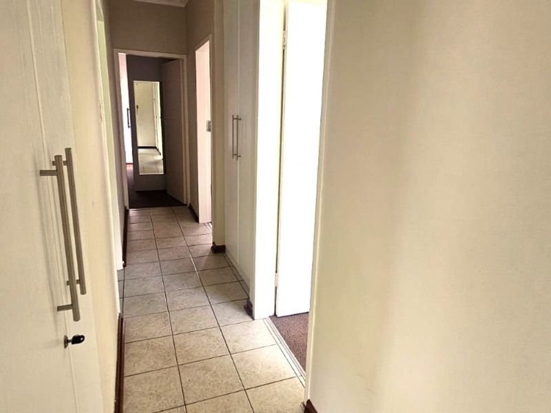 A functional hallway featuring tiled flooring and built-in storage cupboards, providing access to multiple rooms within the townhouse.