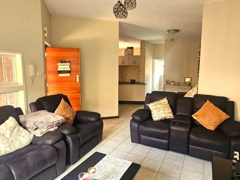 Open plan living area featuring tiled flooring and direct access to a kitchen space with built-in cabinetry.