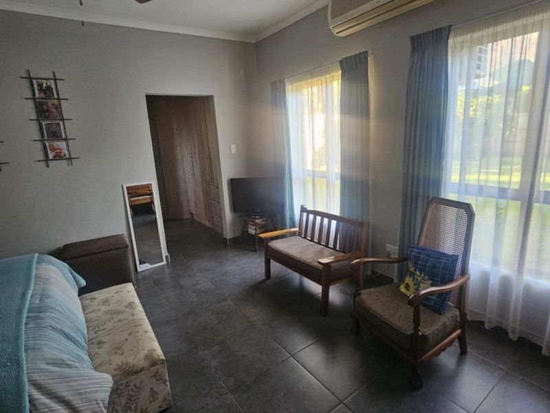 A bedroom featuring tiled flooring, a ceiling fan, and a wall-mounted air conditioning unit, with access to built-in storage.