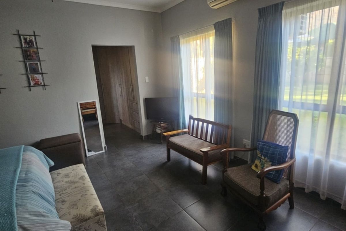 A bedroom featuring tiled flooring, a ceiling fan, and a wall-mounted air conditioning unit, with access to built-in storage.