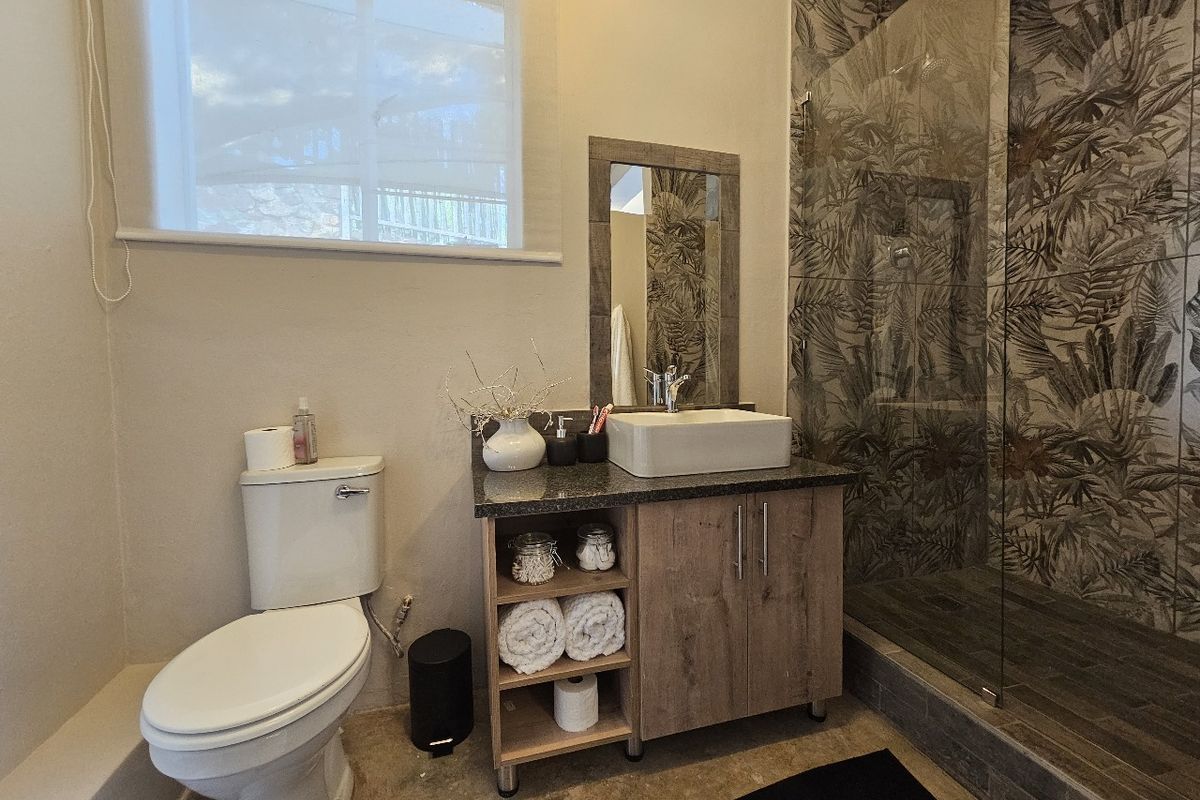 Modern bathroom featuring a vessel sink on a wood-finish vanity, a walk-in shower with decorative patterned tiles, and a clean, contemporary layout.