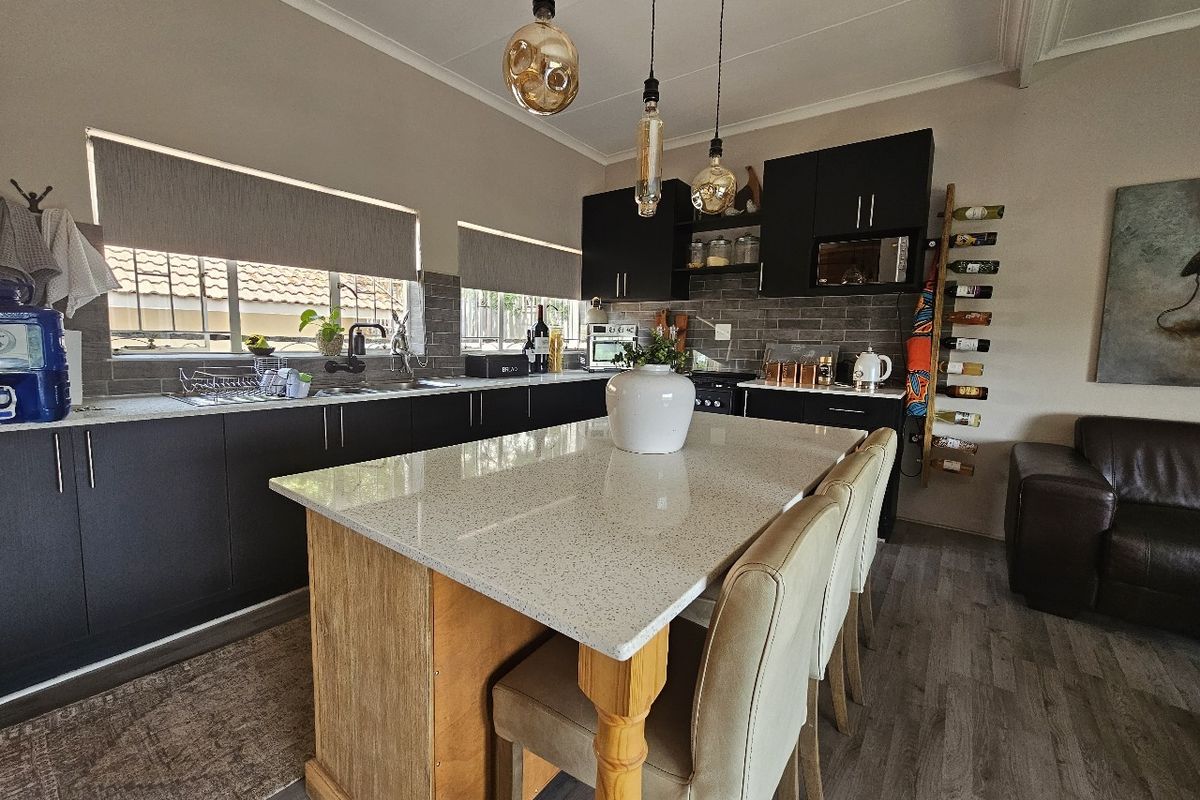 Modern kitchen featuring dark cabinetry, a central island with quartz countertops, subway tile backsplash, and contemporary pendant lighting.