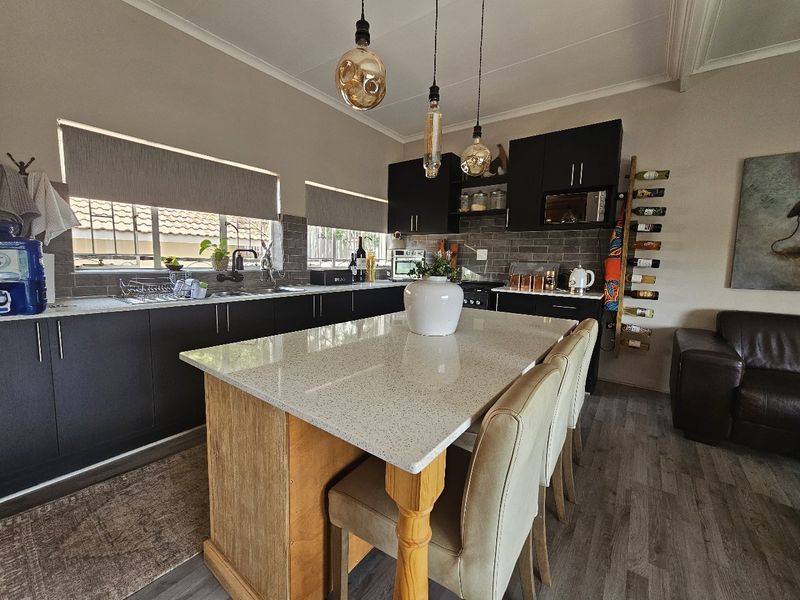 Modern kitchen featuring dark cabinetry, a central island with quartz countertops, subway tile backsplash, and contemporary pendant lighting.