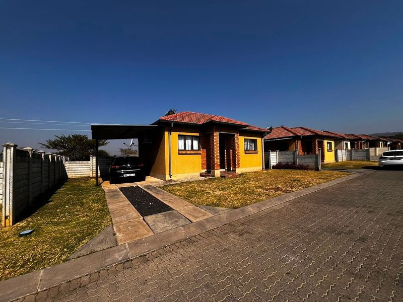 Front exterior view of a townhouse featuring a tiled roof, brick accents, a private carport, and a paved driveway within a residential complex.