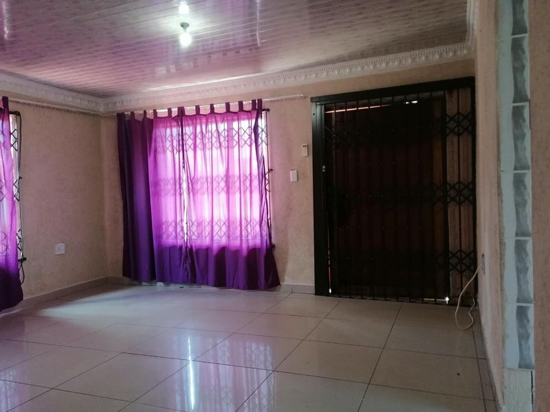 An empty living room featuring tiled flooring, a security gate, and coved ceiling details, offering a blank canvas for potential interior updates.
