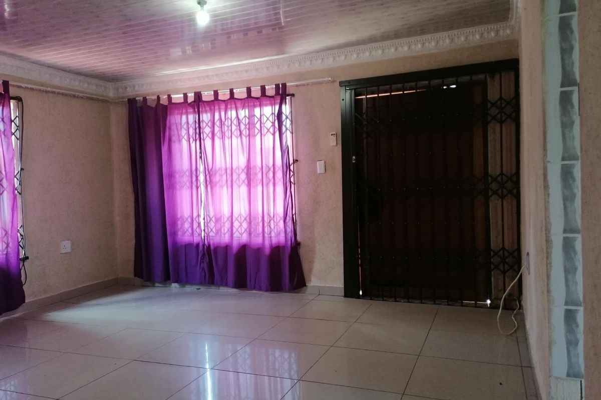 An empty living room featuring tiled flooring, a security gate, and coved ceiling details, offering a blank canvas for potential interior updates.