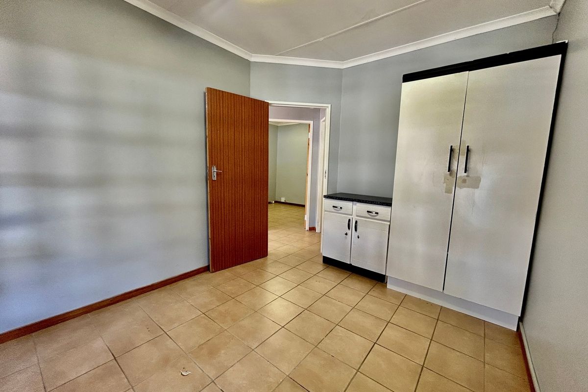 A vacant bedroom featuring tiled flooring, built-in cupboard storage, and neutral wall finishes, offering a clean canvas for personalization.