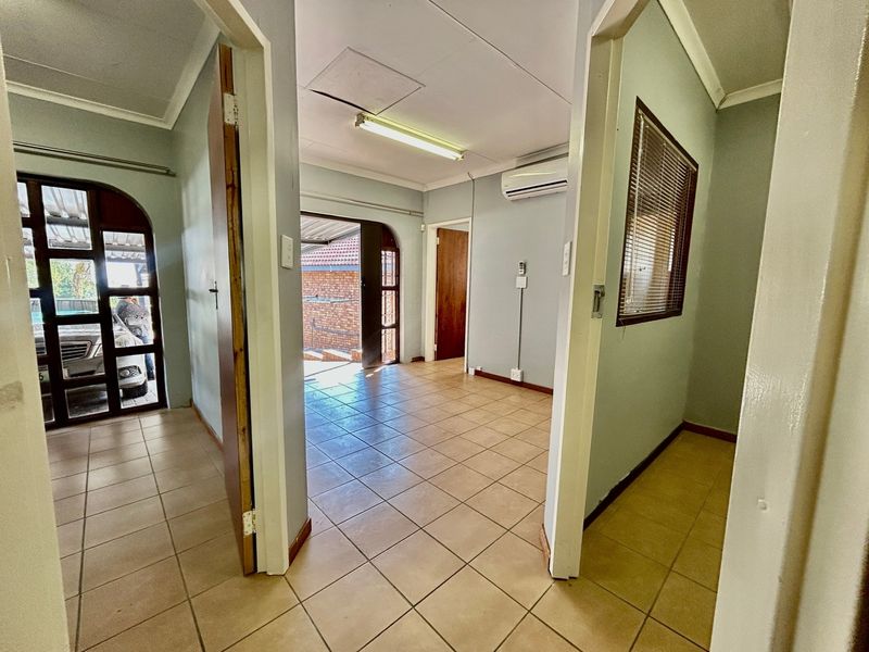 A vacant hallway area featuring tiled flooring, an air conditioning unit, and access to adjacent rooms through archway door frames.