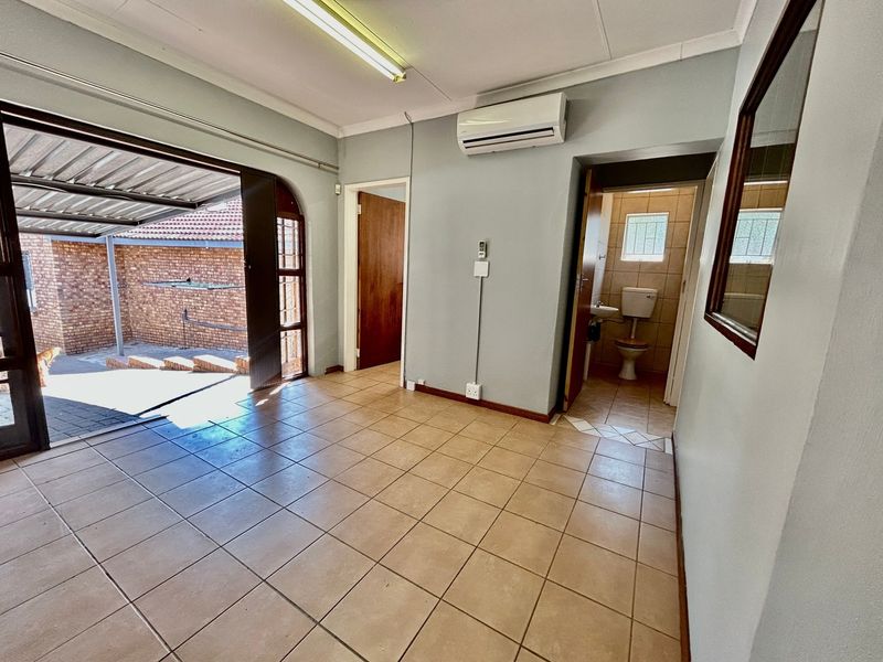 An open-plan living area featuring tiled flooring, an air conditioning unit, and direct access to an outdoor patio area.