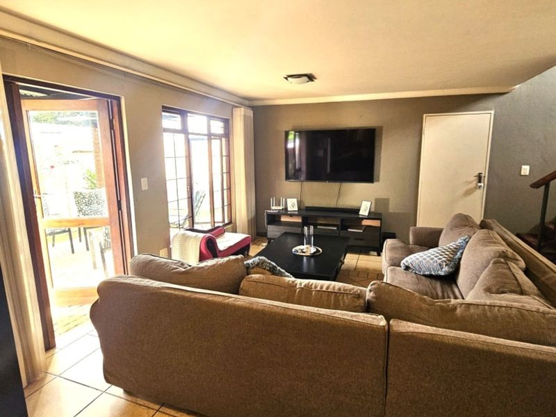 A comfortable living room featuring tiled flooring, large windows, and a sliding glass door providing direct access to the outdoor patio area.