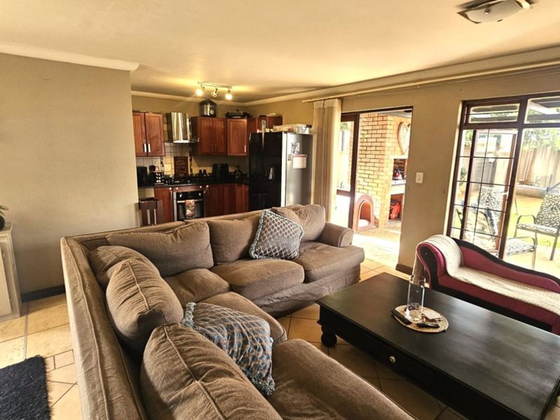 Open-plan living area featuring tiled floors and a functional kitchen, with direct access to an outdoor patio space through sliding glass doors.