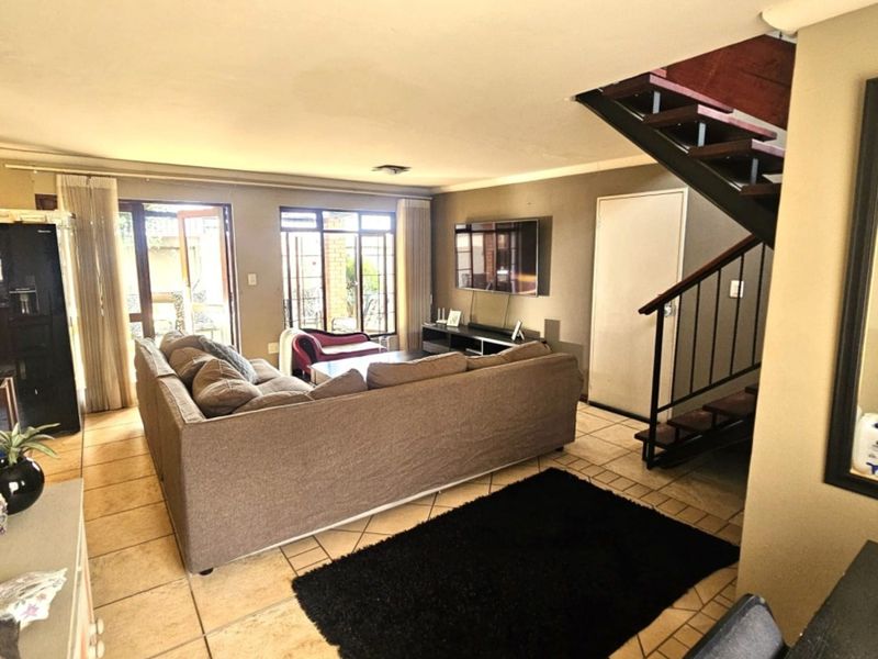 Open-plan living area featuring tiled flooring, a staircase with metal balustrades, and direct access to the outdoor patio through sliding glass doors.