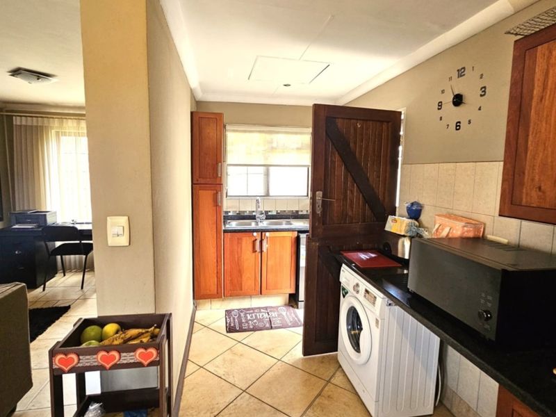 A functional scullery area featuring wooden cabinetry, tiled flooring, a double basin sink, and a stable door leading to the exterior.