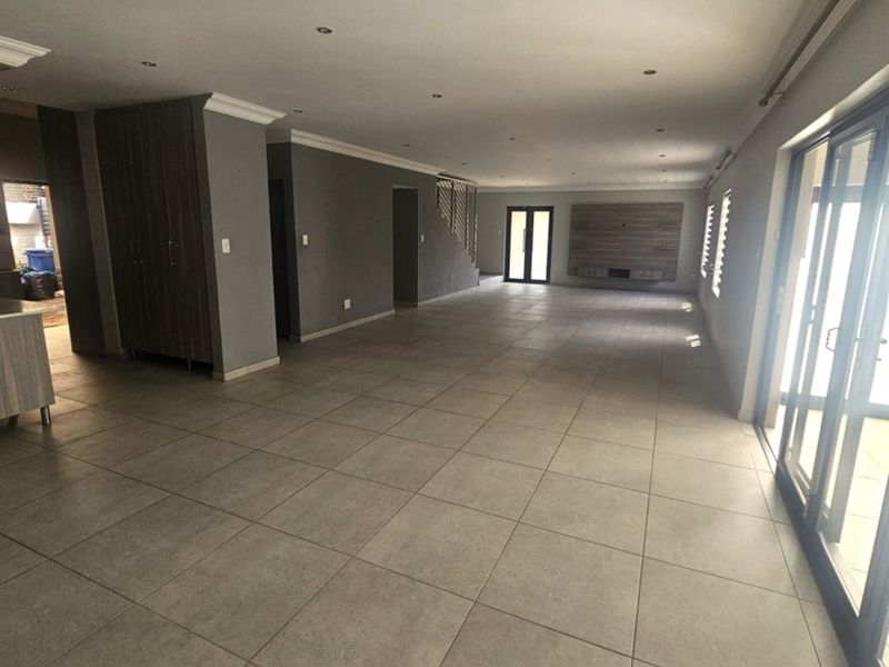 Spacious open-plan living area featuring large format floor tiles, recessed lighting, built-in cabinetry, and sliding glass doors leading to the exterior.