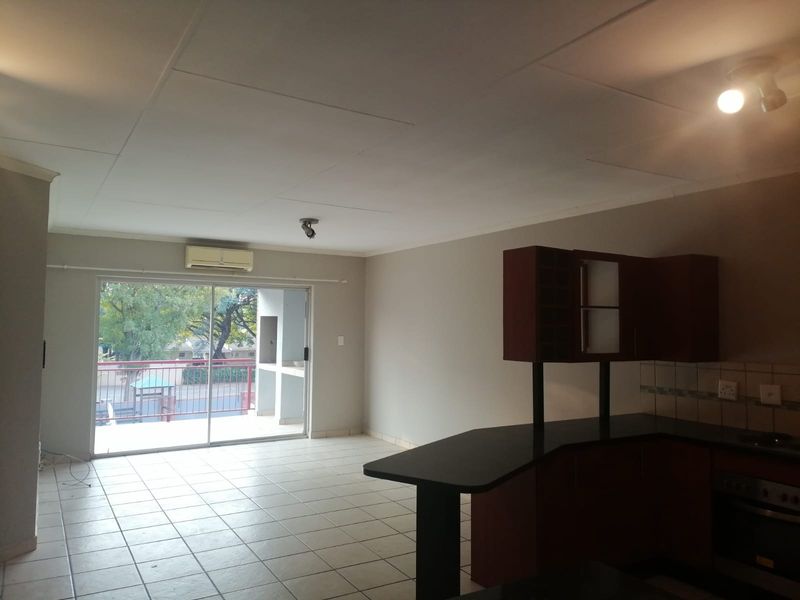 Open-plan living area featuring tiled floors, a functional kitchen with built-in cabinetry and granite countertops, and direct access to a balcony.