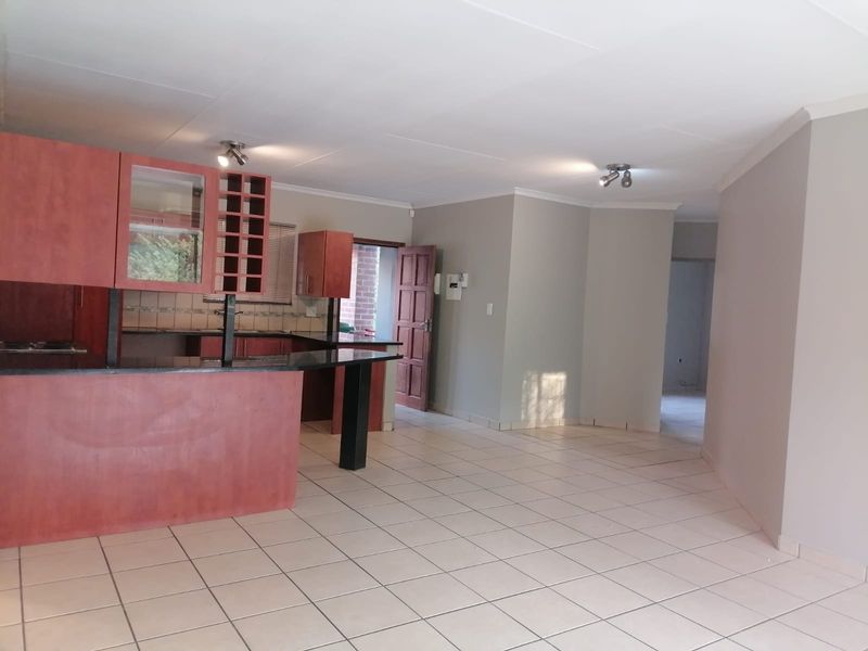 Spacious open-plan living area featuring a kitchen with built-in cabinetry, granite countertops, and neutral tiled flooring throughout.
