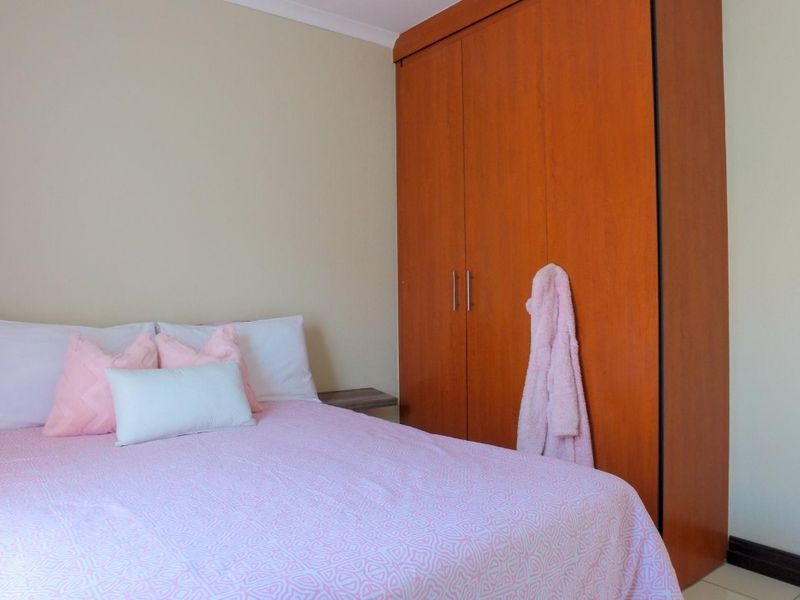 A bedroom featuring a built-in wooden wardrobe and integrated floating bedside shelves, providing functional storage and a clean layout.