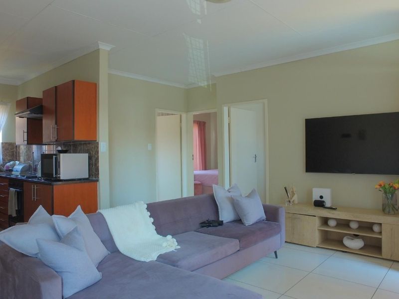 Open-plan living area featuring a functional kitchen with built-in cabinetry and tiled flooring, seamlessly connected to the lounge space.