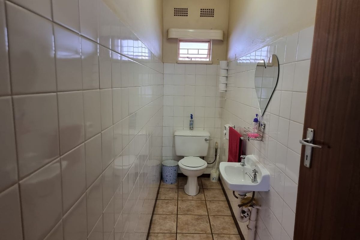 A compact guest bathroom featuring white wall tiles, a pedestal basin, and a standard toilet suite.