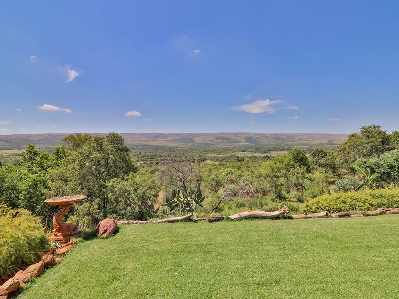 Expansive scenic view overlooking the lush green farm landscape and rolling hills under a clear blue sky.