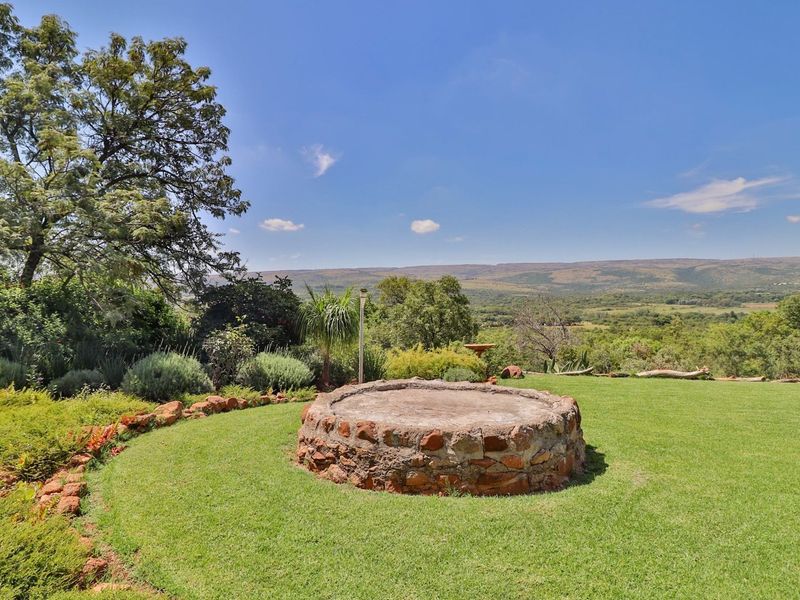 A landscaped garden area featuring a circular stone-built structure with expansive views of the surrounding rural landscape.