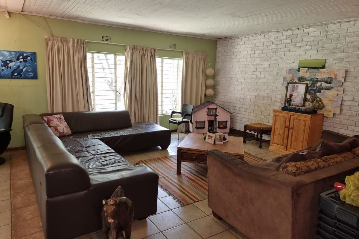Spacious living room featuring a white painted brick feature wall, tiled flooring, and large windows with curtains.