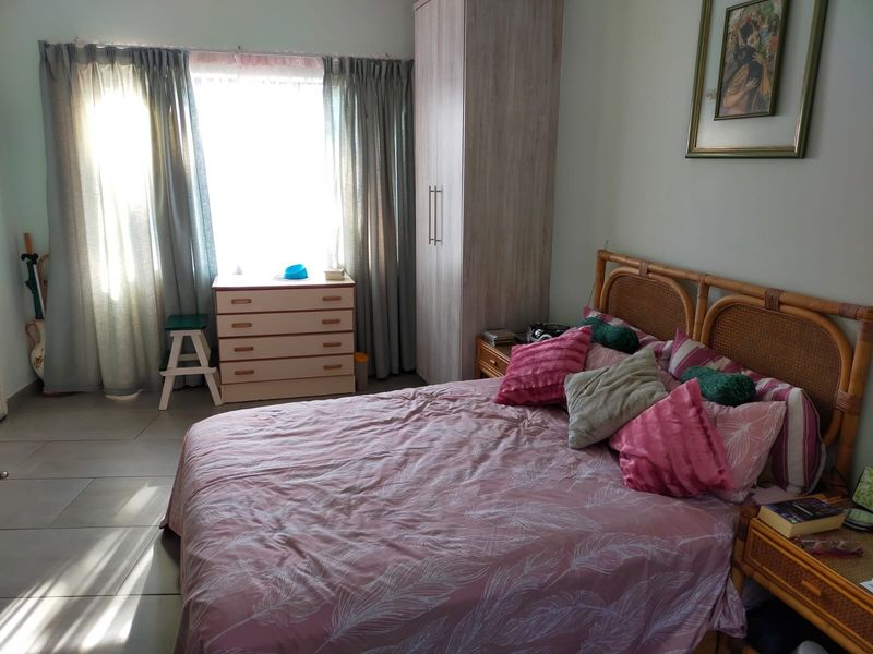 A bedroom featuring tiled flooring and a built-in wardrobe, with natural light entering through a window.