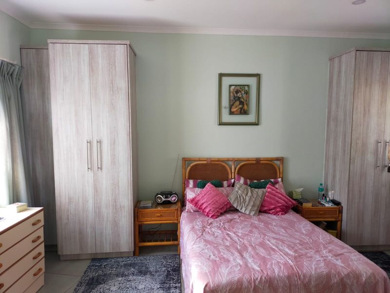 A bedroom featuring light wood-finish built-in wardrobes and neutral wall paint, providing a functional and well-lit sleeping space.