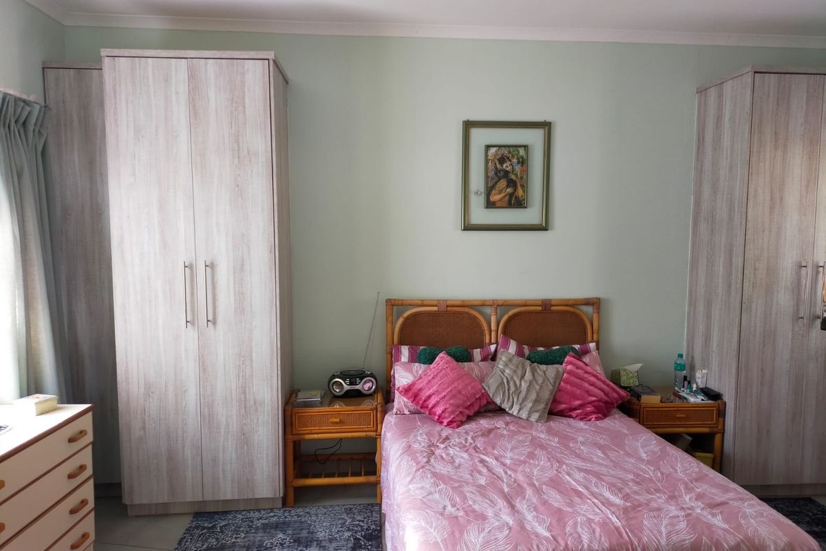 A bedroom featuring light wood-finish built-in wardrobes and neutral wall paint, providing a functional and well-lit sleeping space.