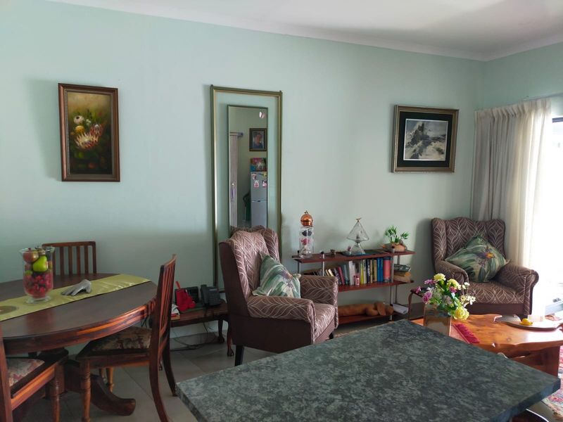 A comfortable living and dining area featuring neutral wall tones, coving, and large windows with curtain rails, offering a functional and well-maintained living space.