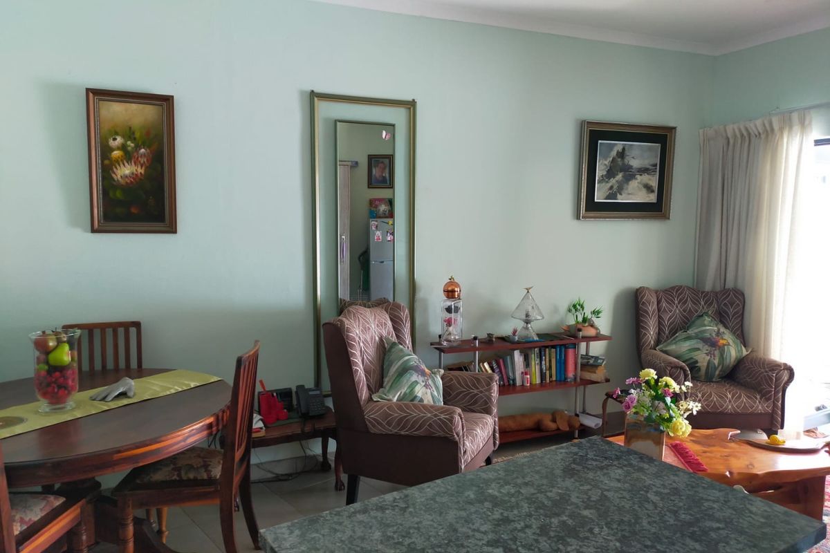 A comfortable living and dining area featuring neutral wall tones, coving, and large windows with curtain rails, offering a functional and well-maintained living space.
