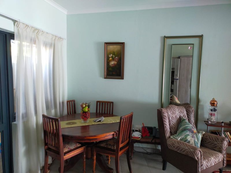 A dining area featuring tiled flooring, coved ceilings, and a sliding glass door providing natural light.