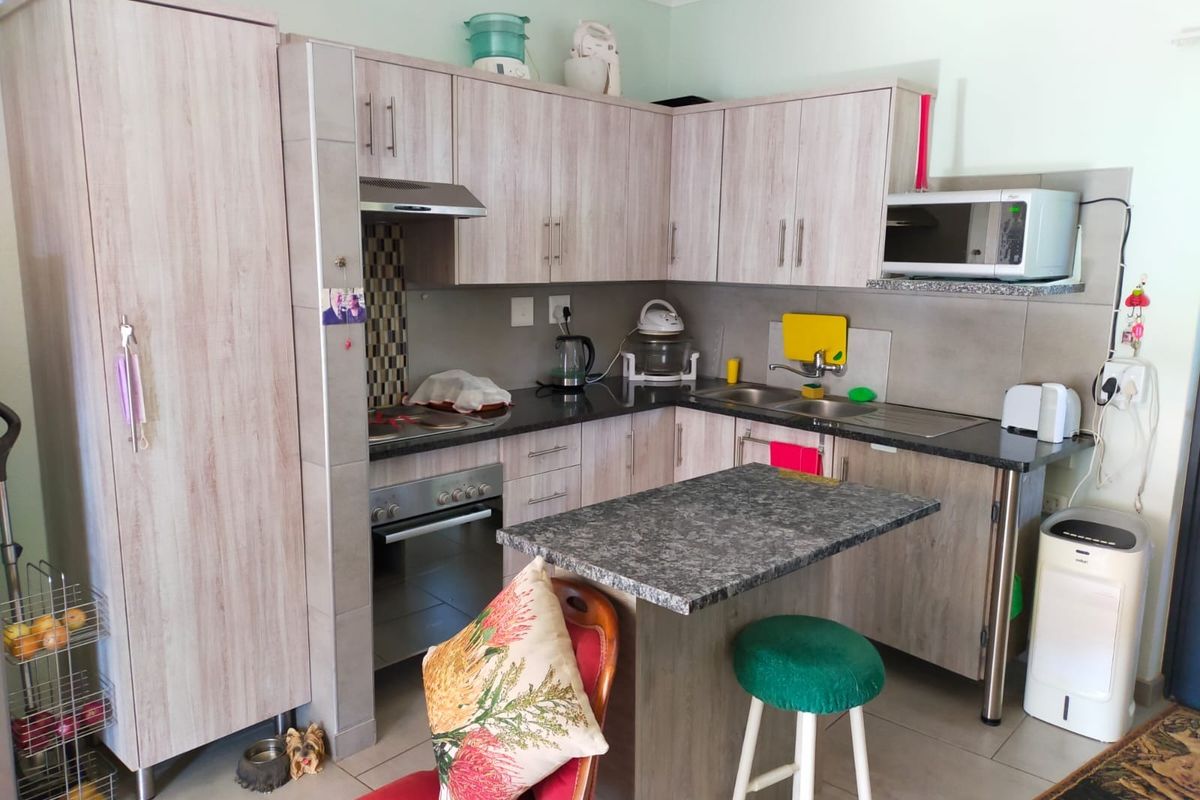 A functional kitchen featuring light wood-grain cabinetry, granite countertops, a built-in oven with extractor fan, and a convenient breakfast nook.