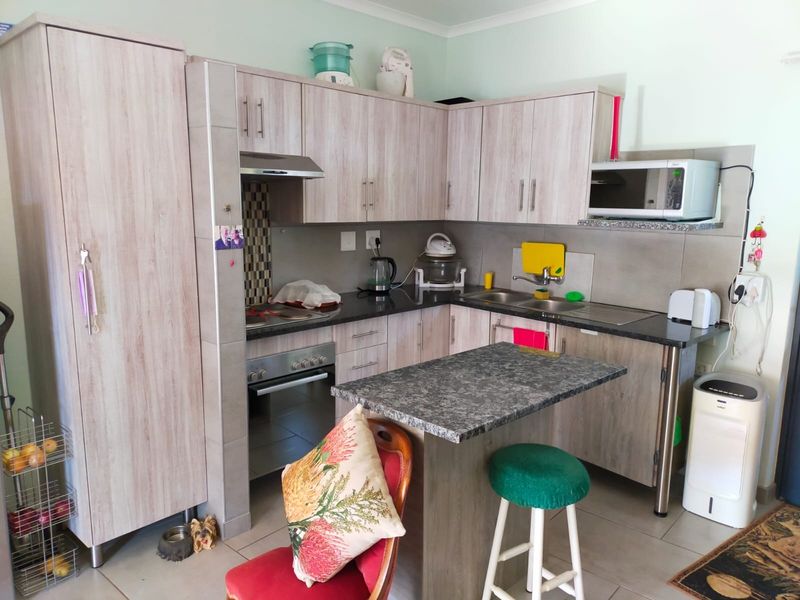 A functional kitchen featuring light wood-grain cabinetry, granite countertops, a built-in oven with extractor fan, and a convenient breakfast nook.