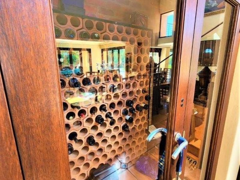 A dedicated wine cellar featuring a custom built-in honeycomb-style wine rack, enclosed by a glass door with timber framing.