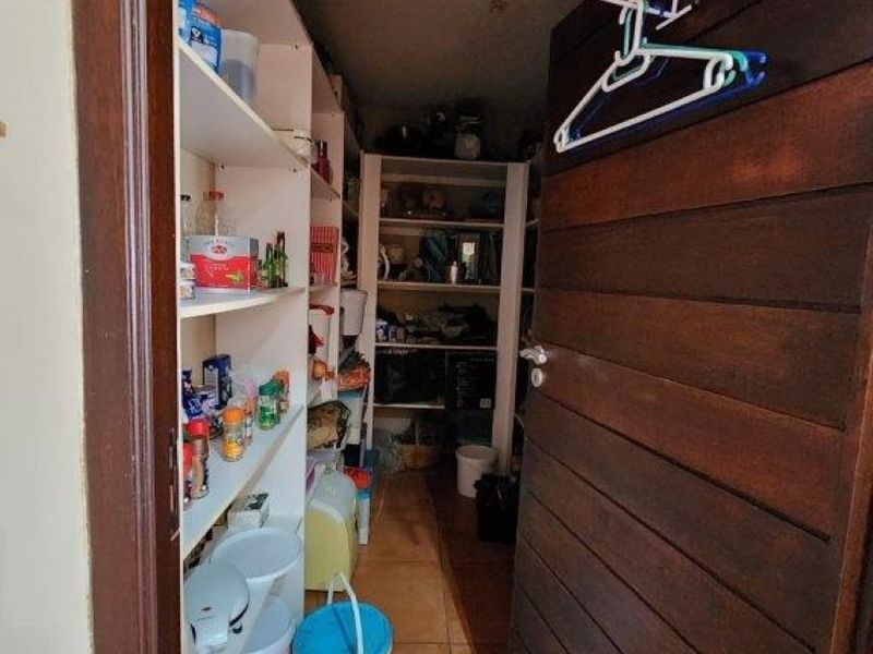 A functional scullery or pantry area featuring extensive built-in shelving and durable tiled flooring, providing ample storage space for household items.