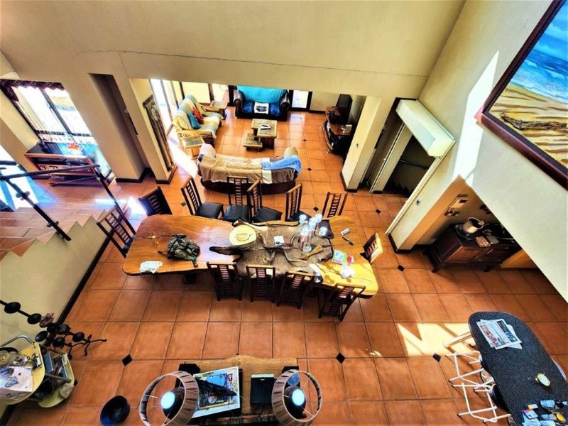 Spacious open-plan living and dining area featuring double volume ceilings, tiled flooring, and a central kitchen island, offering a versatile layout for entertaining.