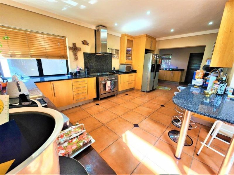 Spacious kitchen featuring wooden cabinetry, granite countertops, a breakfast bar, and a stainless steel gas stove with an extractor fan.