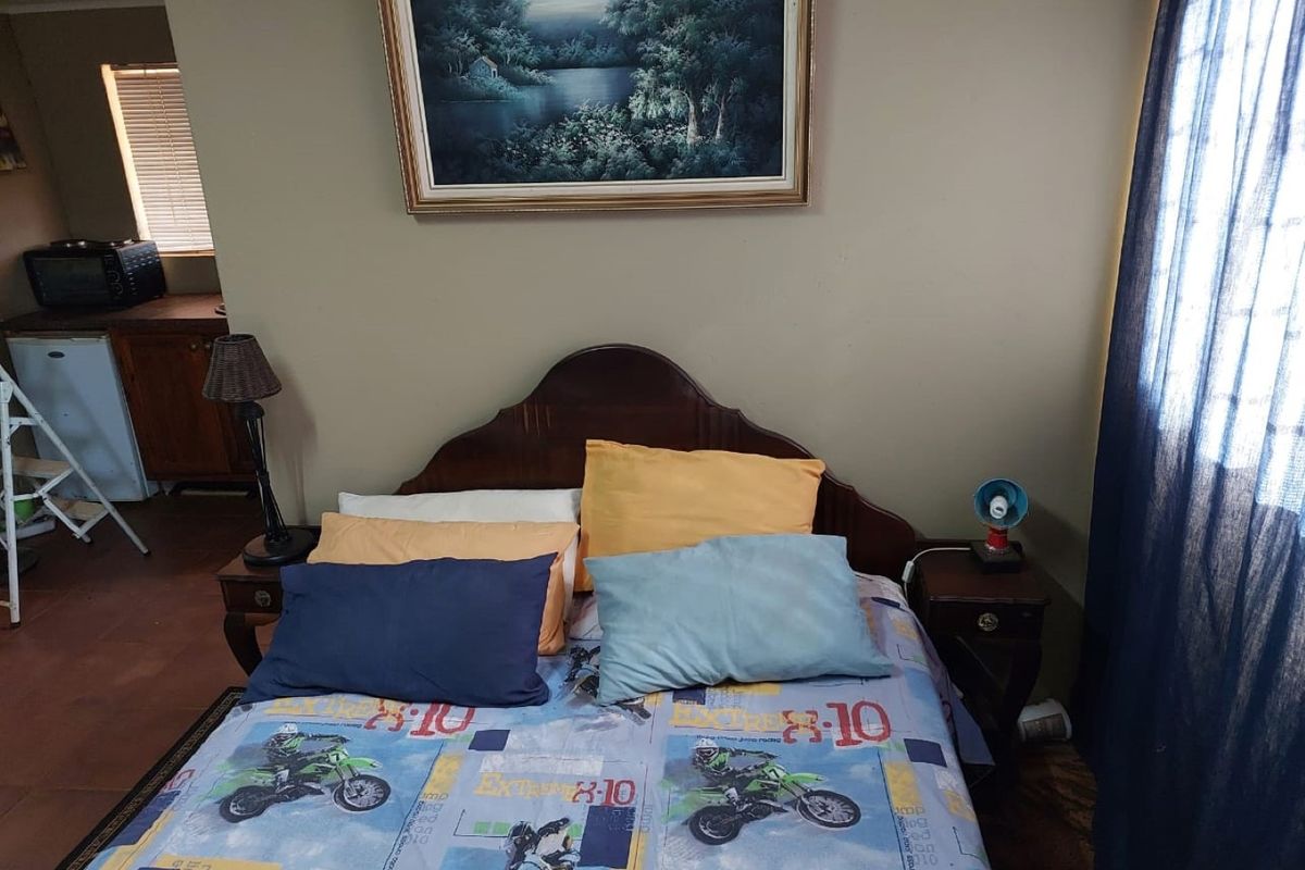 A bedroom featuring a wooden headboard and bedside tables, with a view into an adjacent utility area.