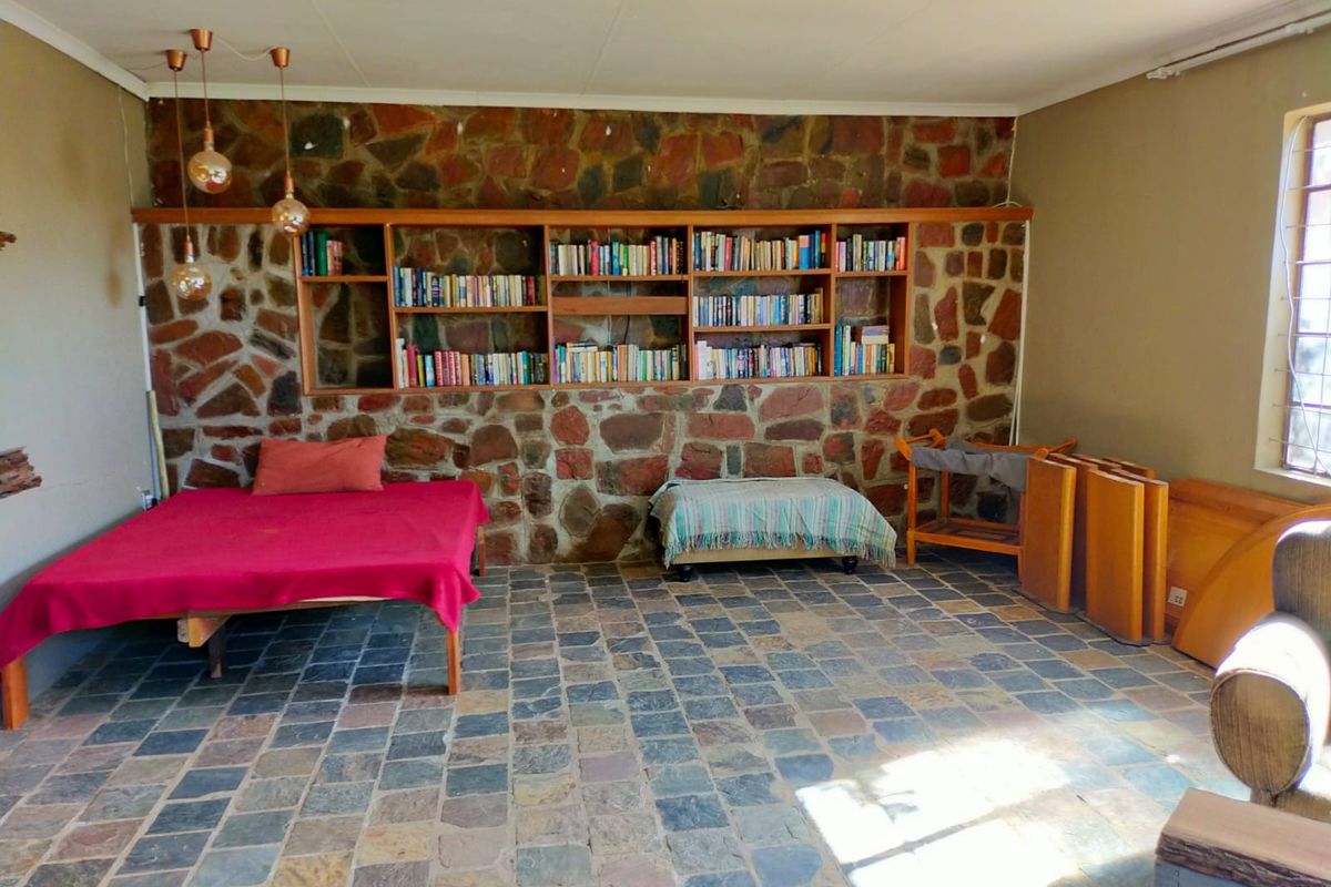 Spacious living area featuring a rustic natural stone feature wall with built-in wooden shelving and durable stone tile flooring.
