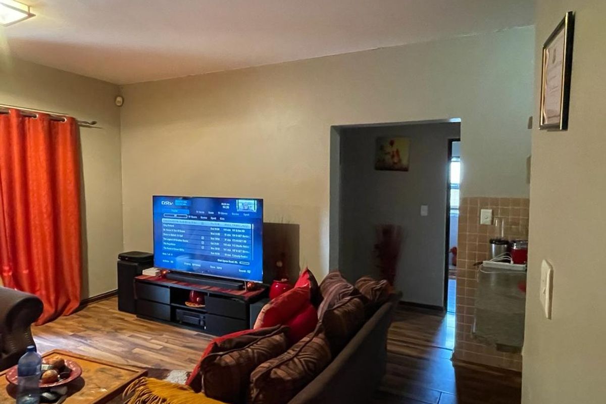 A living room featuring wood-look flooring and a transition area leading to an adjacent space.