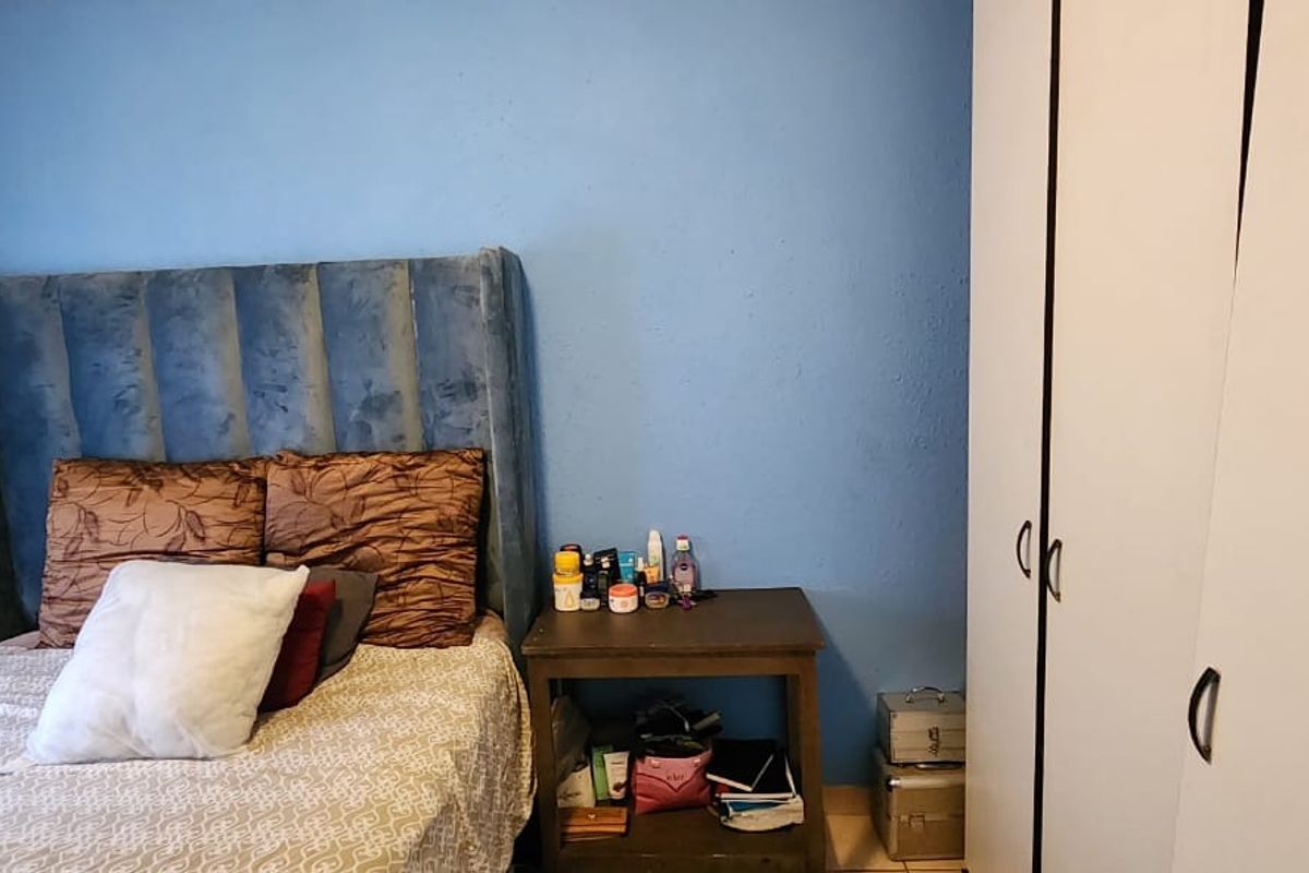 A bedroom featuring built-in white wardrobes and blue painted walls, providing functional storage space.