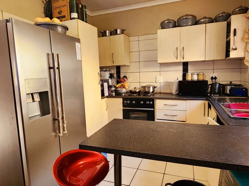 A functional kitchen featuring built-in cabinetry, a dark laminate countertop, a built-in oven and hob, and tiled flooring.