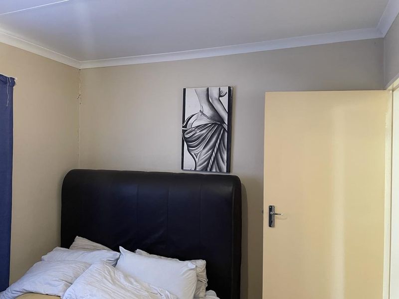 A standard bedroom featuring neutral wall tones, cove cornicing, and a solid internal door with a lever handle.
