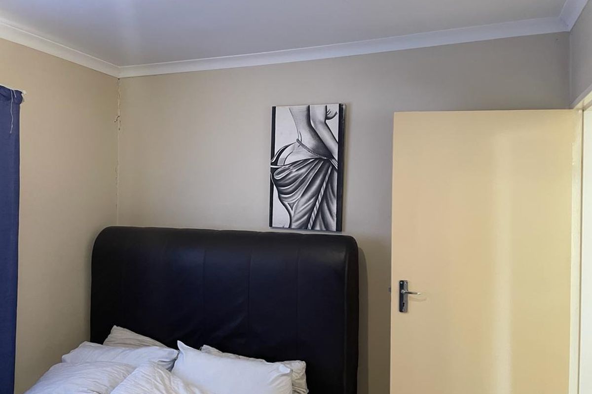 A standard bedroom featuring neutral wall tones, cove cornicing, and a solid internal door with a lever handle.