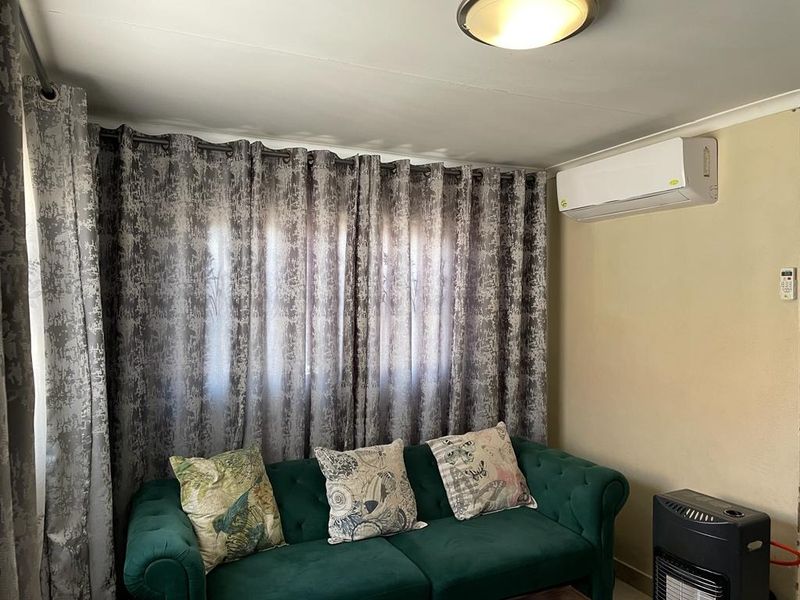 A living room featuring a wall-mounted split-system air conditioner and a central ceiling light fixture.