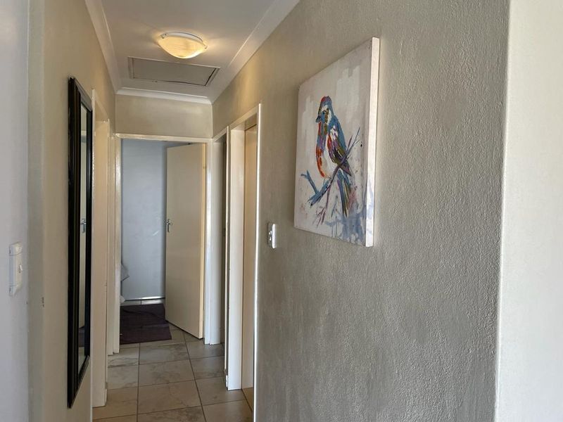 A functional hallway featuring tiled flooring, neutral wall finishes, and a ceiling access hatch, providing access to adjacent rooms.