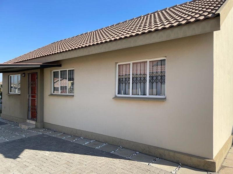 A well-maintained exterior view of the house featuring a tiled roof, paved driveway, and secure window and door fittings.
