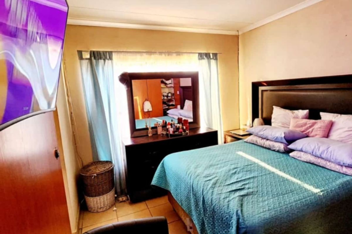 A functional bedroom featuring tiled flooring, a ceiling-mounted light fixture, and a window with curtain tracks.