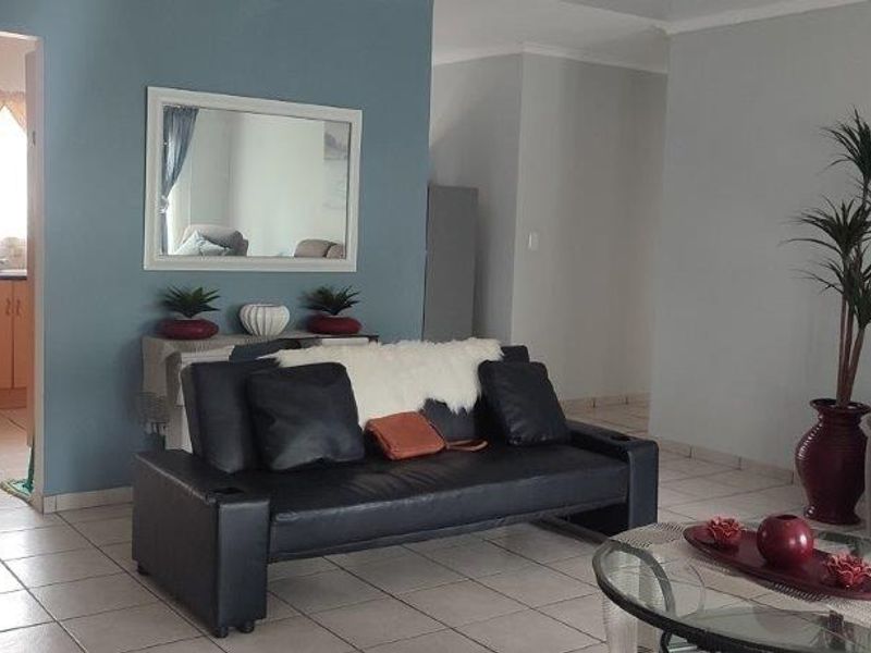 Open-plan living area featuring tiled flooring and a view through to the kitchen area with built-in cabinetry.